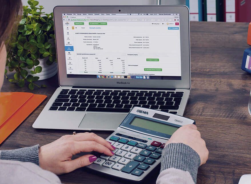 Accounting professional using a calculator and laptop